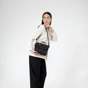 Woman holding a black handbag against a white background