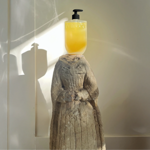 Yellow bottle with black pump on a stone sculpture against a light background