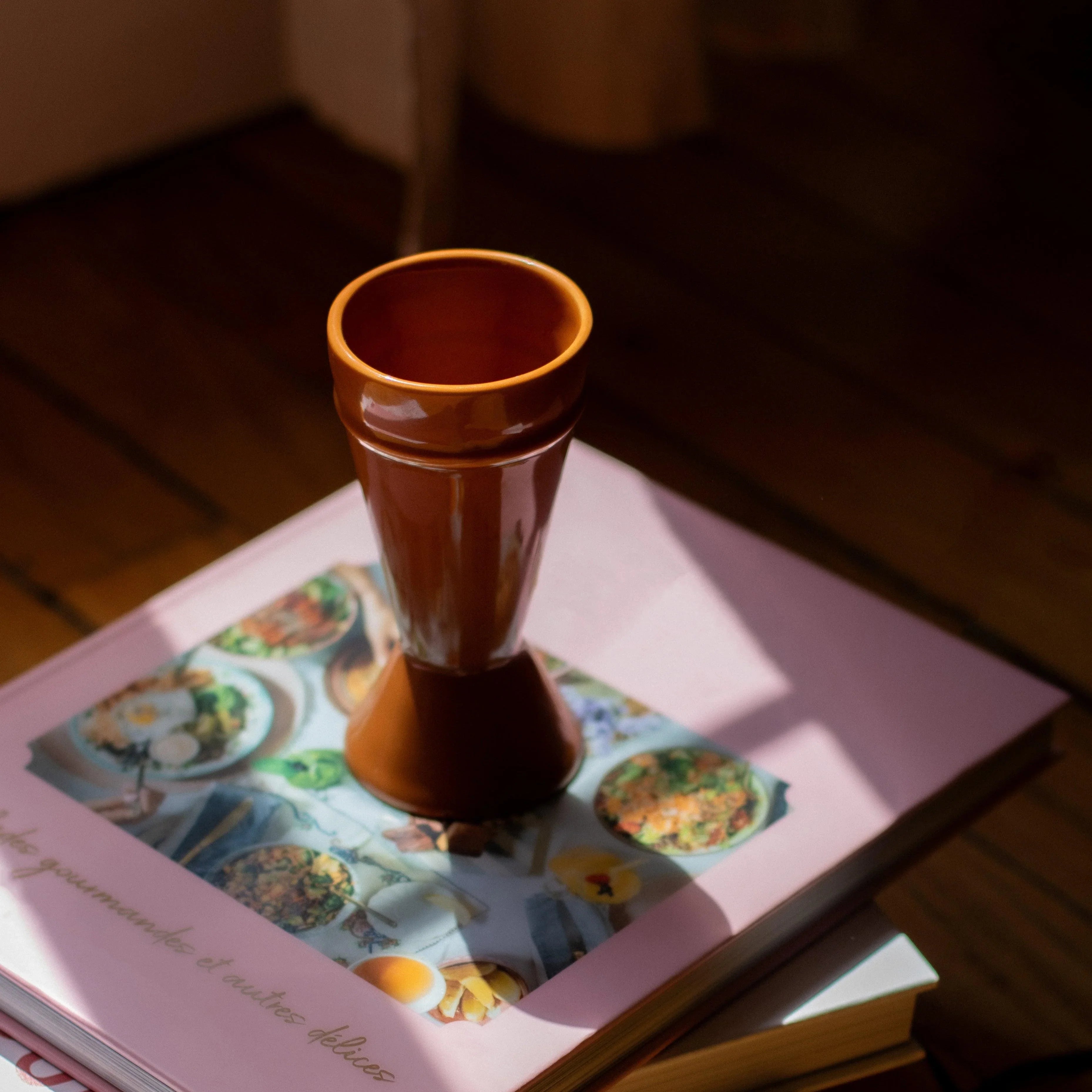 Caramel Mazagran made from upcycled clay sitting on a stack of pink covered  books