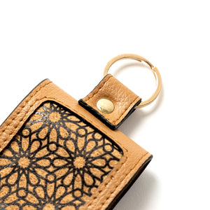 Beige leather keychain with floral pattern on a white background