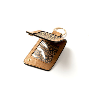 Brown leather keychain with a clear window and gold accents on a white background