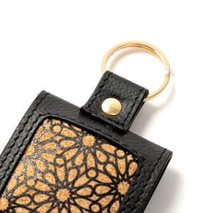 Black leather keychain with gold geometric pattern on a white background