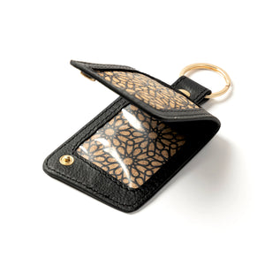 Black leather keychain with gold floral pattern on a white background