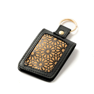 Black leather keychain with gold geometric pattern on a white background