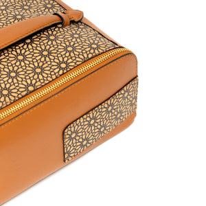 Tan cosmetic case with intricate black pattern on a white background