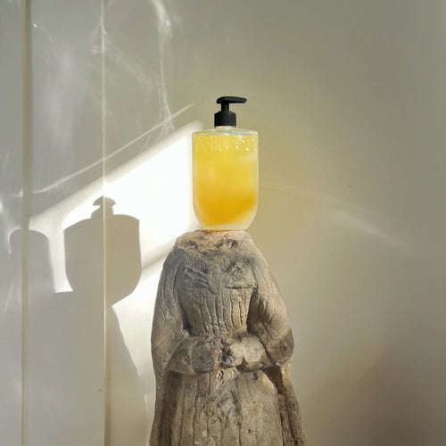 Yellow bottle with black pump on a stone sculpture against a light background