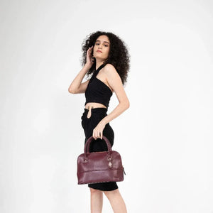 Woman holding a burgundy handbag against a white background