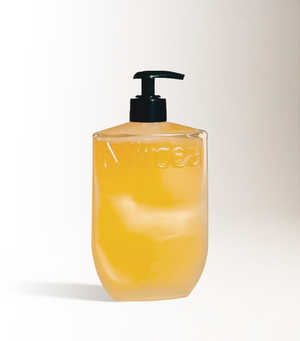 infinitely refillable glass bottle with black pump on a light beige background