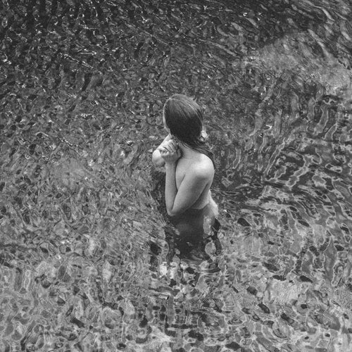 Person standing in water with a textured stone wall background