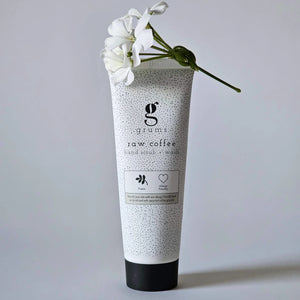 Skincare product with a white flower on a gray background featuring grums coffee oil hand scrub