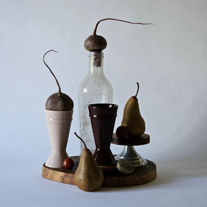 Two mazagran coffee cups arranged on a dark wooden board with long rooted beetroot