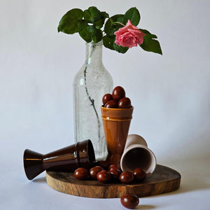 Three Mazagran Coffee Cups arranged on a dark wooden board with bright red cherries and a pink rose