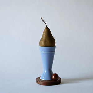 blue mazagran coffee cup on a dark wooden board against a white background