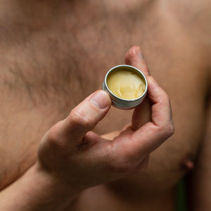 man holding a tin of grums vegan lip balm