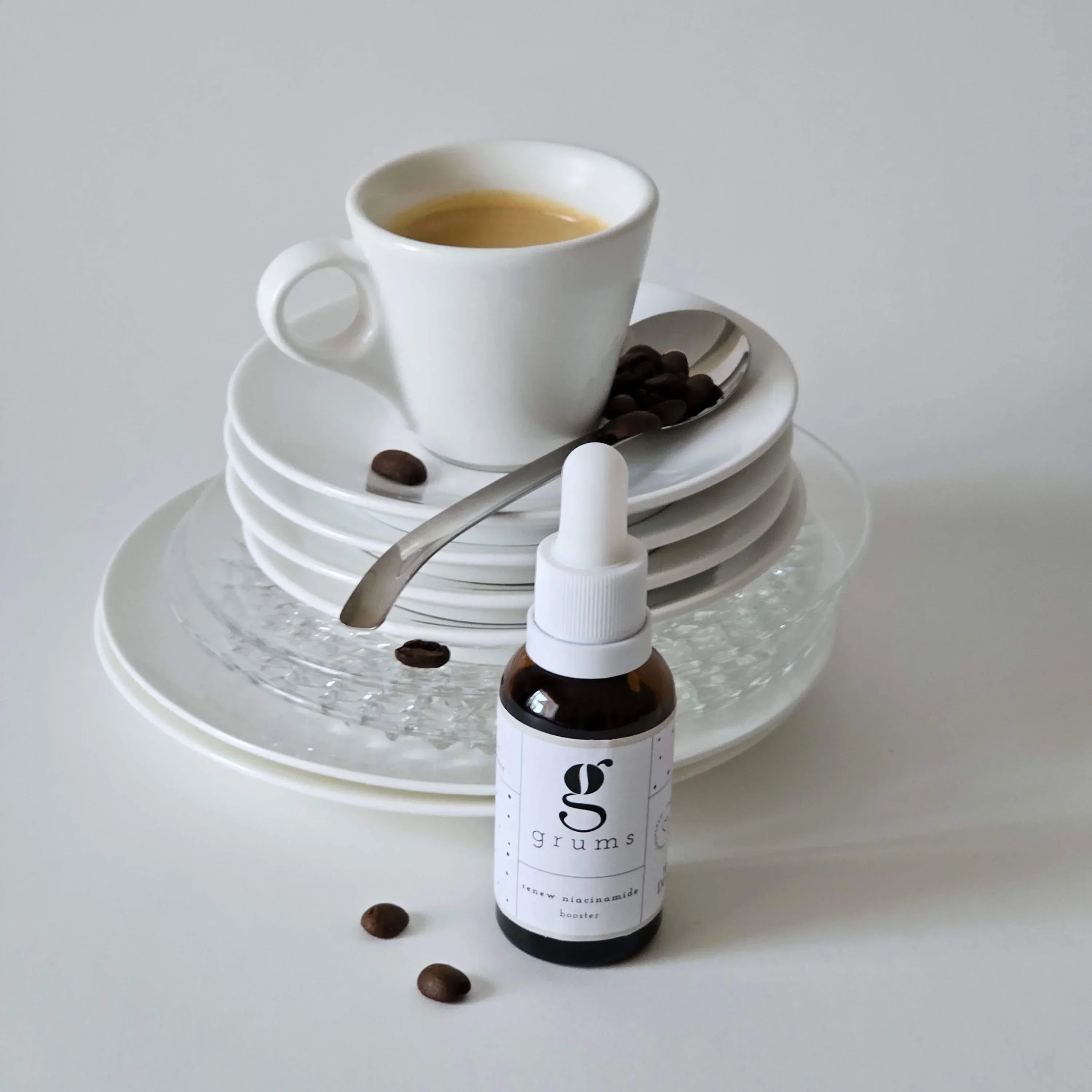 Bottle of Grums coffee creamer with a cup of coffee and saucers on a white background