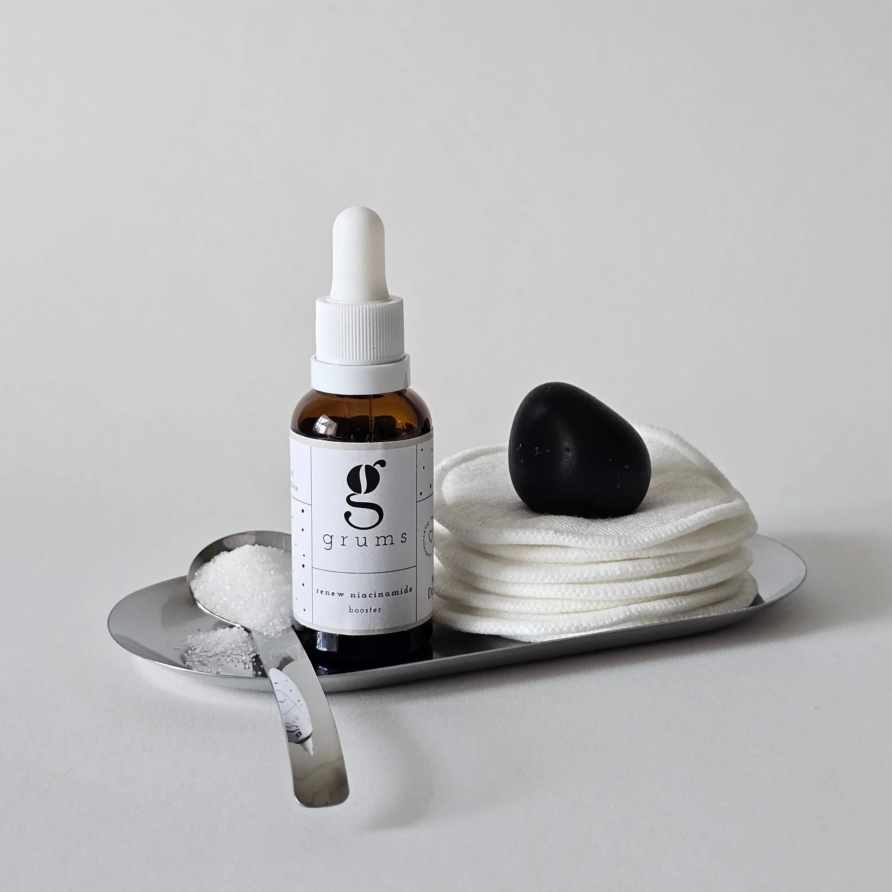 Skincare product with dropper on a white plate against a light gray background