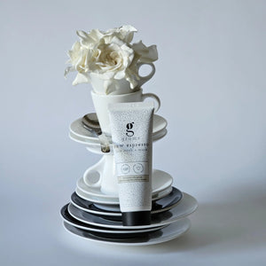 grums espresso face scrub and mask styled against a stack of cups and saucers with a large white rose