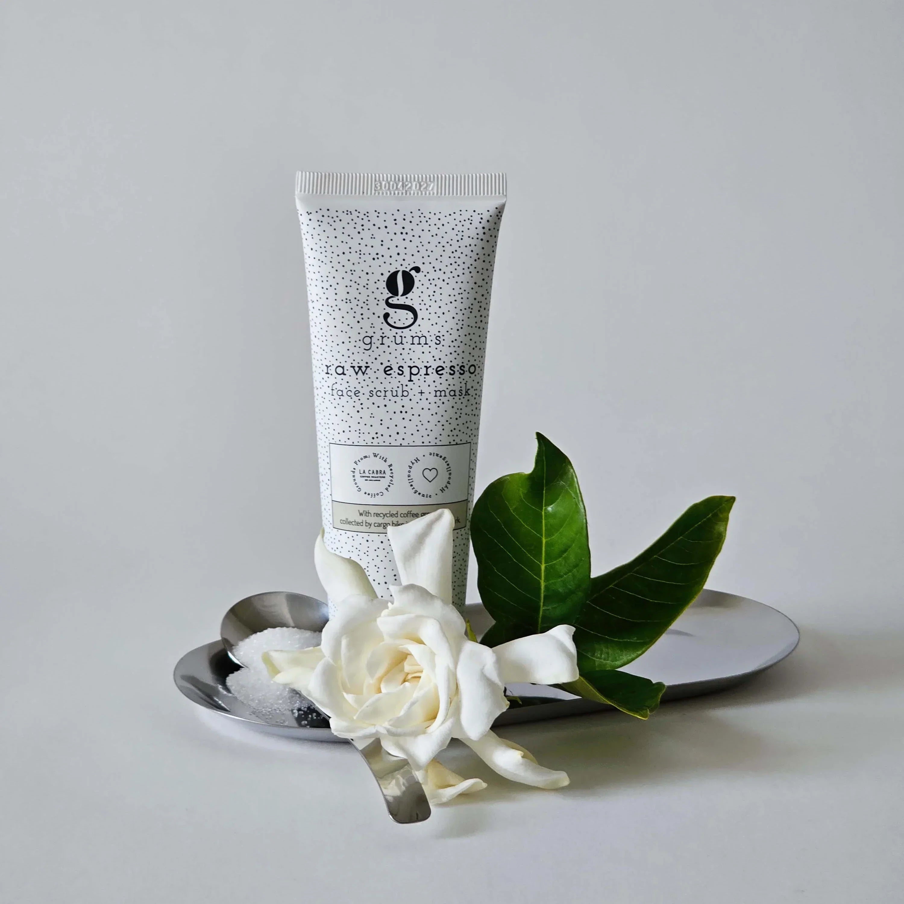 Tube of skincare product with flowers on a gray background