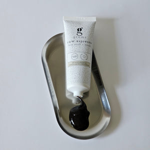 Tube of grums espresso facial scrub & mask tube open showing texture on a metallic tray with a white background