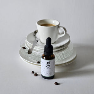 grums hydra calm serum made with coffee oil sitting in front of a coffee cup and saucer