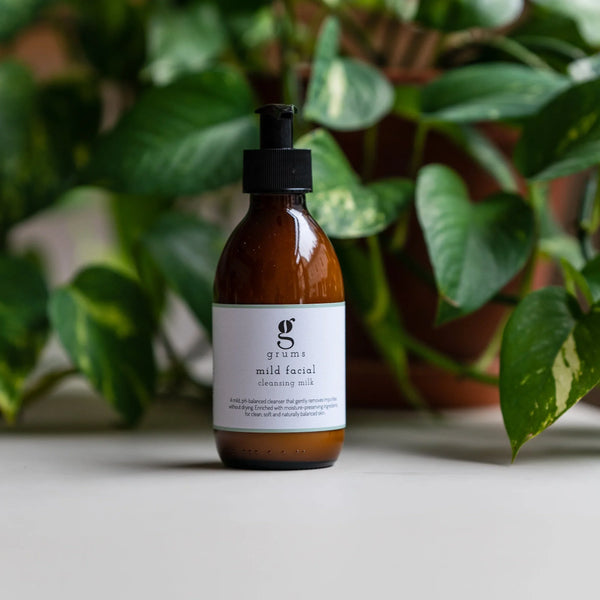 Brown bottle with black cap on a light surface with green plants in the background