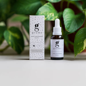 Grumas skincare serum bottle and packaging with green leaves in the background