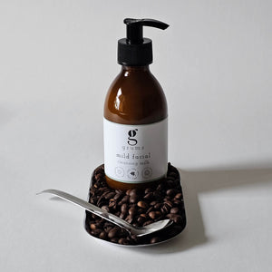 grums vegan facial cleansing milk sitting on a silver tray with coffee beans
