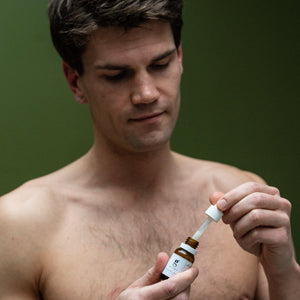 man shown holding a bottle of grums under eye serum made from upcycled coffee grounds oil