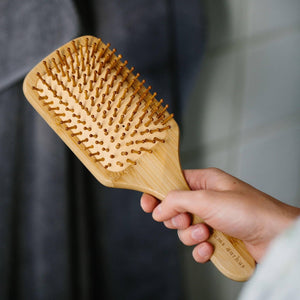 grums Bamboo Hairbrush being held in a hand ready for use