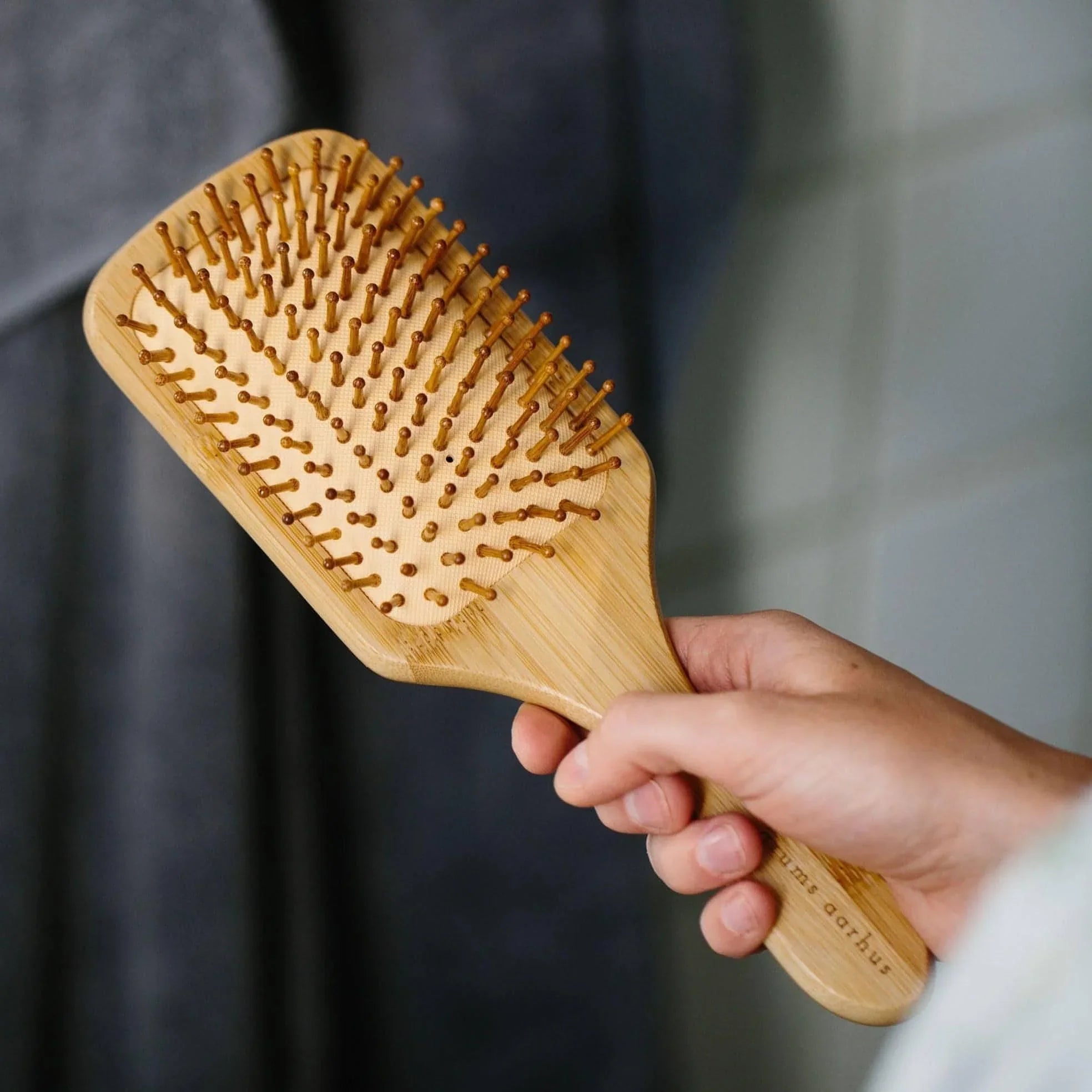grums Bamboo Hairbrush being held in a hand ready for use
